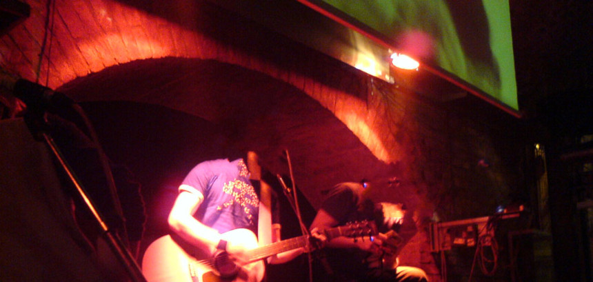 a band on a small stage, a musician playing the guitar